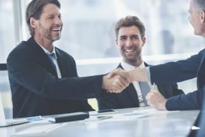 Businessmen shaking hands at the board room table